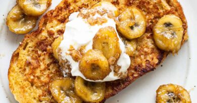 A plate of french toast with bananas and whipped cream.