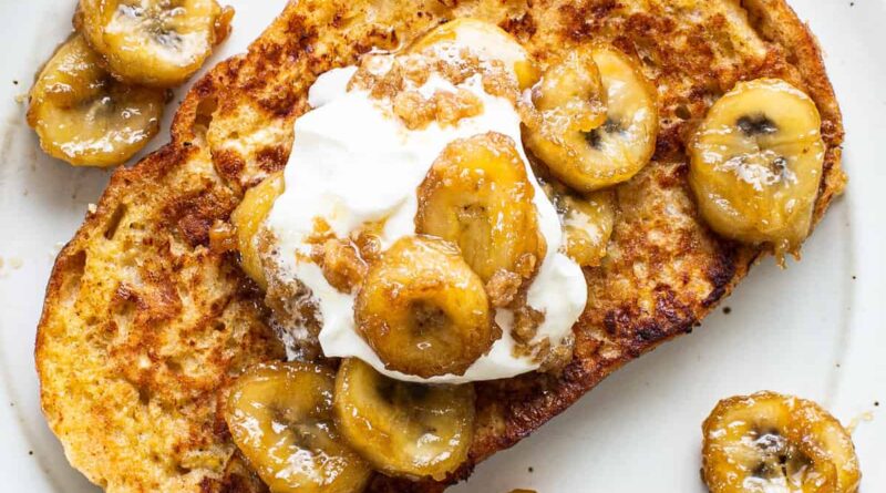 A plate of french toast with bananas and whipped cream.