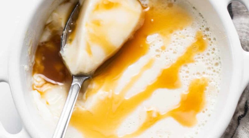 A bowl of ice cream with caramel sauce and a spoon.