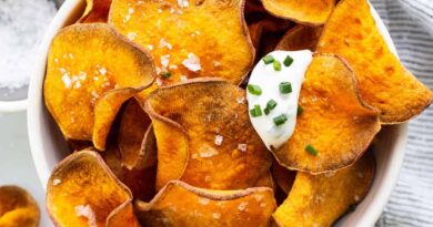 Sweet potato chips in a bowl with sour cream and parsley.