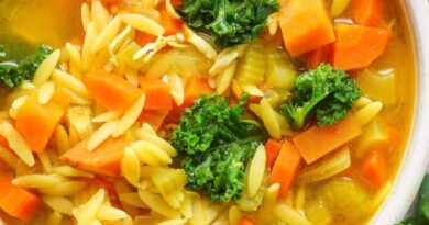 A bowl of soup with carrots and kale.