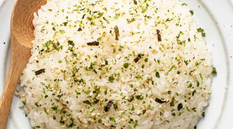 Japanese rice on a white plate with a wooden spoon.