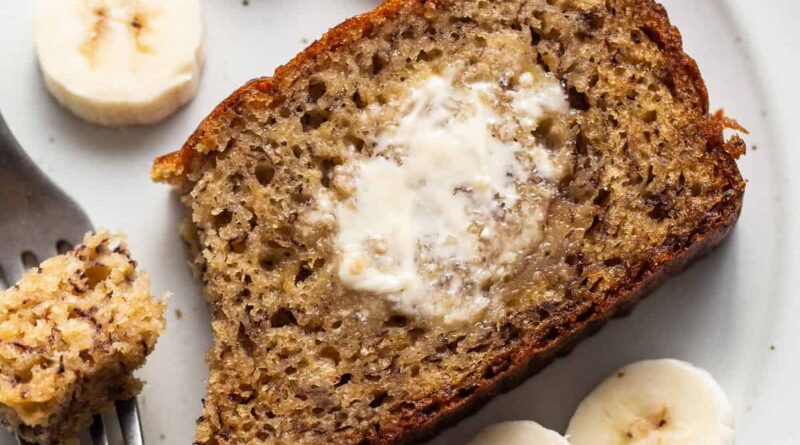 A slice of banana bread on a plate with a fork.