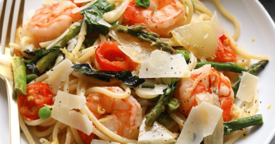 Shrimp scampi with asparagus served over a plate of pasta.