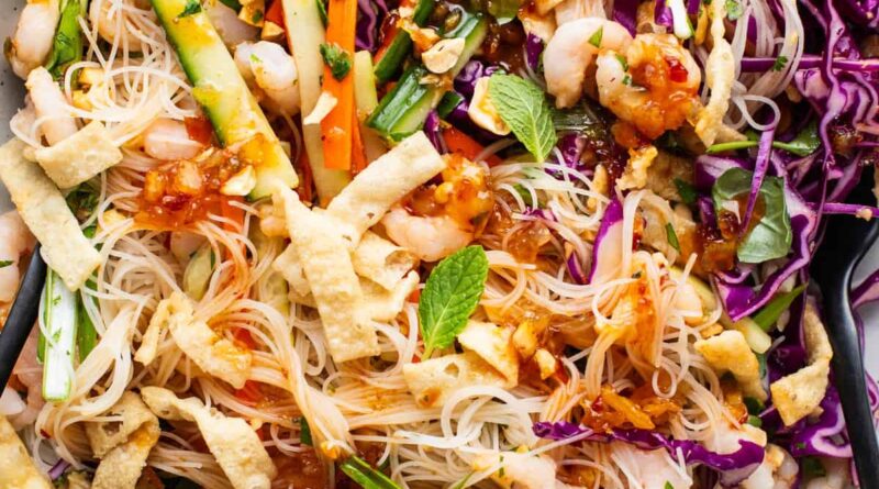 A bowl of asian noodle salad with shrimp and vegetables.