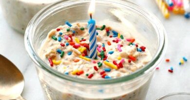 A birthday cake in a jar with sprinkles and a candle made from cake batter overnight oats.