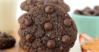 Flourless Double Chocolate Peanut Butter Cookies displayed on a cutting board accompanied by a glass of milk.