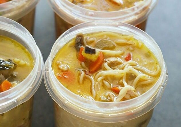 Four plastic containers filled with soup are frozen.