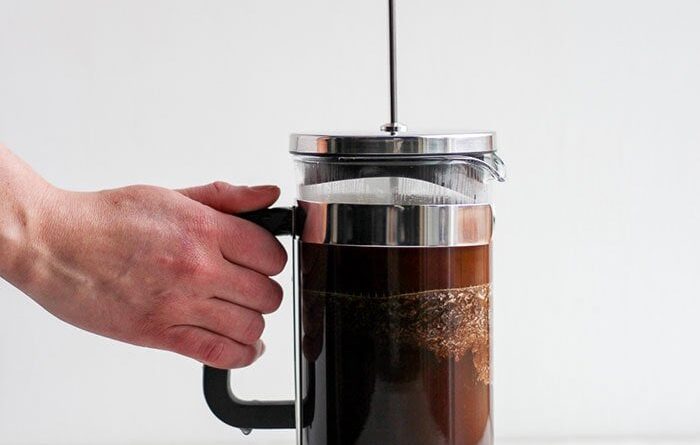 A person making coffee with a French press.