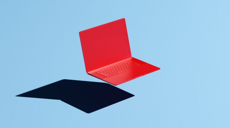 Conceptual image of a red laptop floating mid-air on a blue background with a hard shadow
