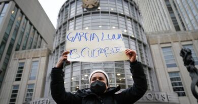 A protester holds a sign that reads, "Garcia Luna is guilty"