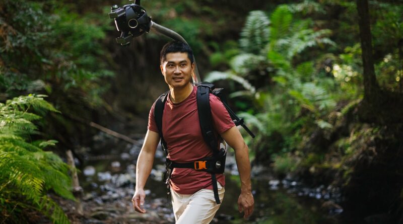 Man hiking in a forest wearing Odyssey camera pack
