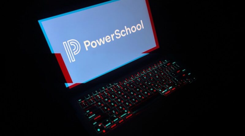 a laptop in a dark room with the laptop keyboard lit up with a red and blue glitchy effect, and the display reads PowerSchool with its corporate logo.