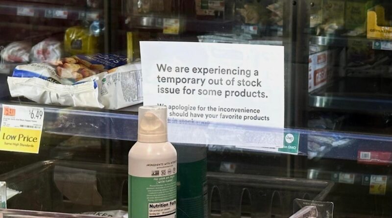 a photo of the frozen and refrigerated section at a local Whole Foods, with empty spaces, and signs warning of an out-of-stock issue.