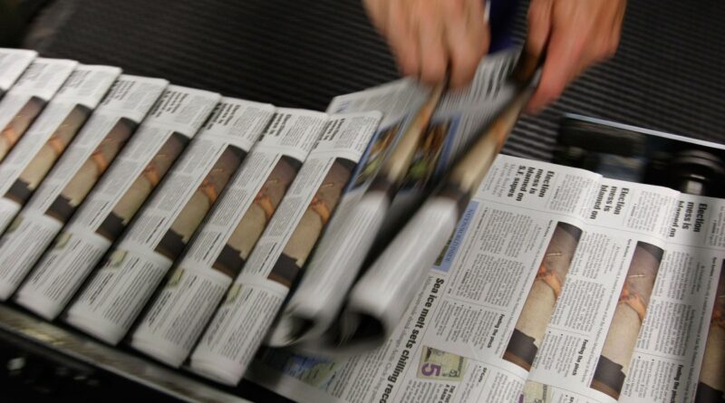 A photo of a stream of newspapers on the printing press.