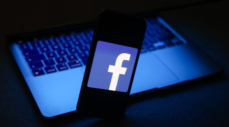 Facebook logo displayed on a phone screen and a laptop are seen in this illustration photo