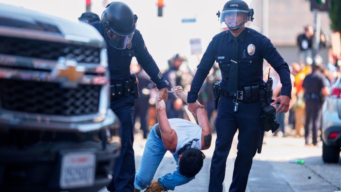 Two officers carry off a handcuffed protester on the streets of Los Angeles
