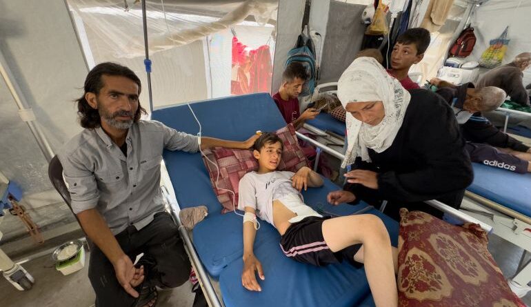 Ihab and Iman Musleh hover near their son's hospital bed in a makeshift tent ward