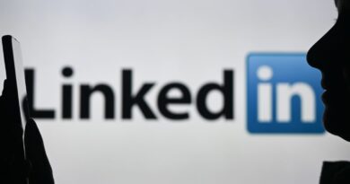 An image of a woman holding a cell phone in front of a LinkedIn logo displayed on a computer screen.