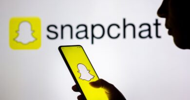 In this photo illustration, a woman's silhouette holds a smartphone with the Snapchat logo displayed on the screen and in the background.