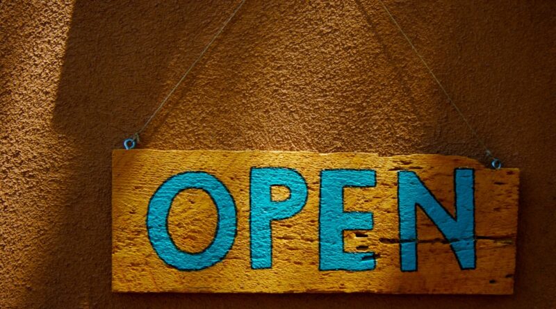 A wooden, hand-painted "Open" sign