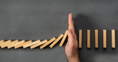 Chain Reaction In Business Concept, Businessman Intervening Dominoes Toppling; cut spending
