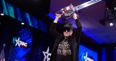 CEO of Tesla and SpaceX Elon Musk holding a chainsaw above his head.
