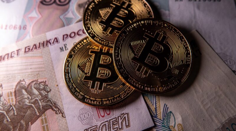 Novelty Bitcoin tokens are photographed besides Russian rouble bank notes.