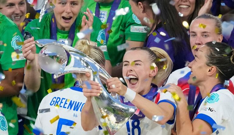 England's Chloe Kelly celebrates with the trophy as goalkeeper Hannah Hampton at left looks on after winning the Women's Euro 2025 final soccer match between England and Spain at St. Jakob-Park in Basel, Switzerland, Sunday, July 27, 2025. (AP Photo/Alessandra Tarantino)