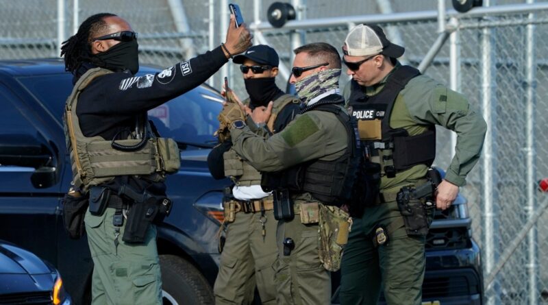 Immigration and Customs Enforcement (ICE) agents use their phones near protestors at a demonstration in Elizabeth, New Jersey May 7, 2025, outside Delaney Hall, a newly converted immigrant detention centre.