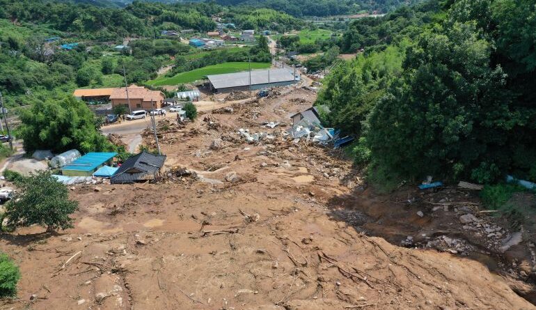 a view of a flooded village with torrents of brown water