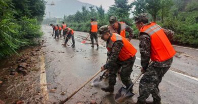 In this photo released by Xinhua News Agency, members of the Chinese People's Armed Police Force clean up silt on a road in Miyun District as continuous rain fall triggers alerts, in north of Beijing on July 27, 2025. (Wang Xiqing/Xinhua via AP)