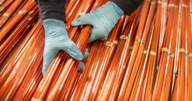 A worker lifts a bundle of copper windings.