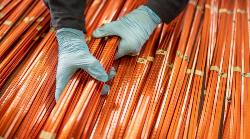 A worker lifts a bundle of copper windings.