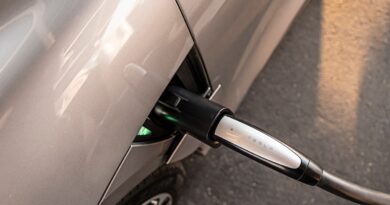 A close up image showing a Tesla charger is plugged into a Lucid Air sedan.