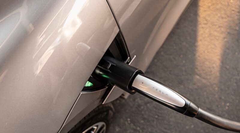 A close up image showing a Tesla charger is plugged into a Lucid Air sedan.