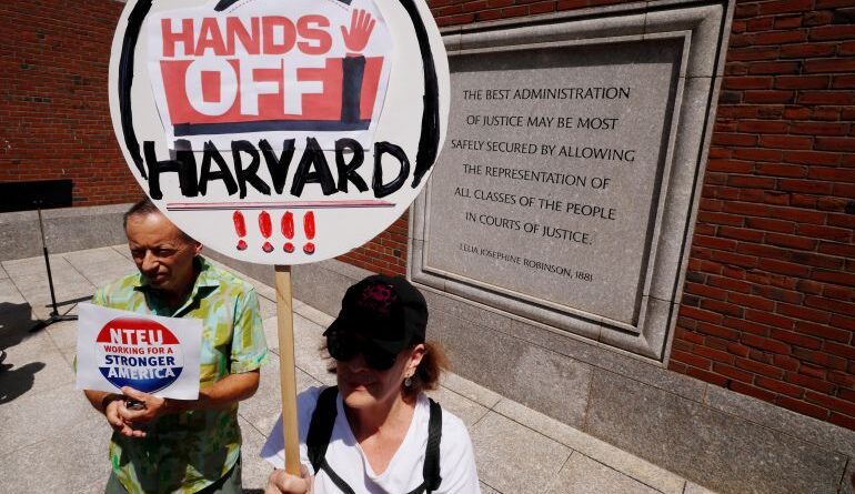 A protester holds up a sign that reads: "Hands off Harvard"