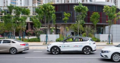 a whilte autonomous vehicle on a city street, with apollo branding