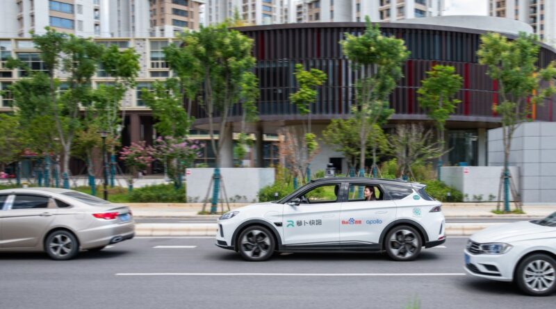 a whilte autonomous vehicle on a city street, with apollo branding