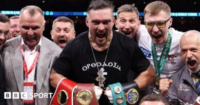 Oleksandr Usyk holds up his arms as Daniel Dubois walks past in the ring at Wembley Stadium