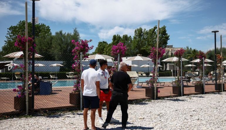 Workers stand near the swimming pool of the 'Le Mimose' resort, where skydiver Felix Baumgartner's paraglider crashed, killing him and injuring a hotel employee on the ground, in Porto Sant'Elpidio, Italy