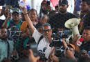 Luis Garcia Villagrain raises a fist in front of media cameras.