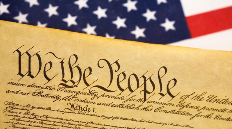 a photo of the US Constitution next to a US flag