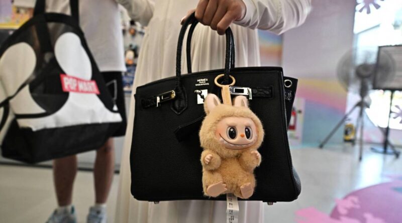 designer art toy Labubu attached to a shopper's handbag at the Pop Mart store in Siam Square in Bangkok. (