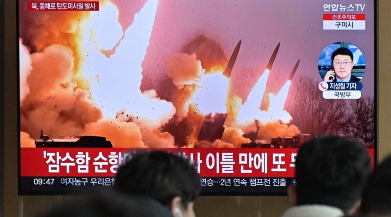 People stand near a television showing a news broadcast with file footage of a North Korean missile test, at a railway station in Seoul on March 14, 2023. - North Korea fired two short-range ballistic missiles on March 14, 2023, Seoul said, Pyongyang's second launch in three days and the first since South Korea and the United States began their largest joint military drills in five years.