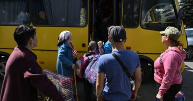 people carrying their belongings get onto a yellow bus