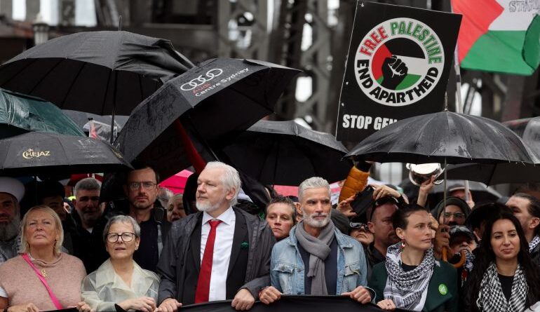 people march behind a banner that says march for humanity save gaza on a bridge