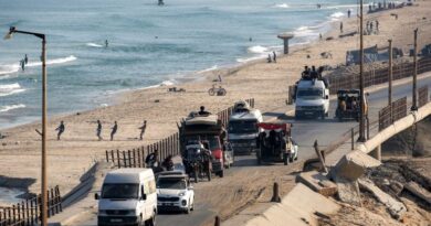 Trucks and vehicles move along the coastal road near fishermen pulling their nets to retrieve their catch on a beach in the Nuseirat camp for Palestinian refugees in the central Gaza Strip
