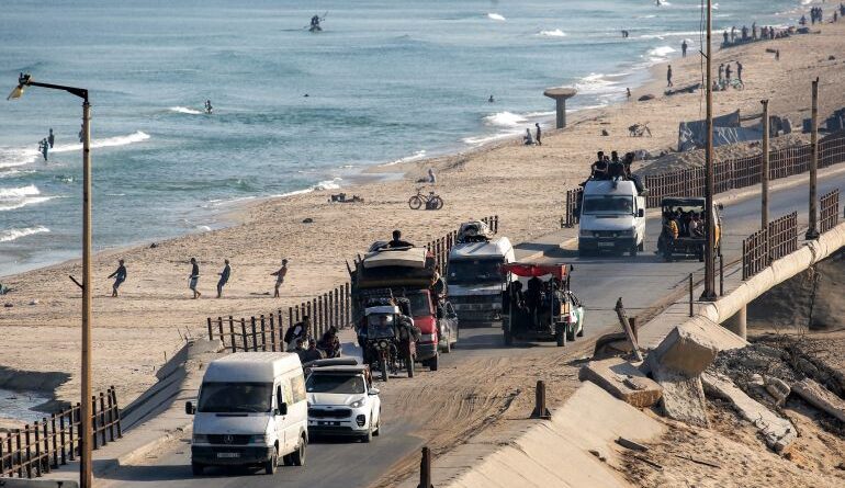 Trucks and vehicles move along the coastal road near fishermen pulling their nets to retrieve their catch on a beach in the Nuseirat camp for Palestinian refugees in the central Gaza Strip