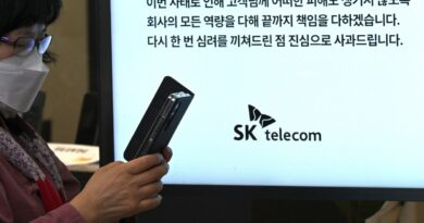A woman uses her mobile phone while waiting to replace her USIM ship in front of an SK Telecom branch in Seoul on April 28, 2025.